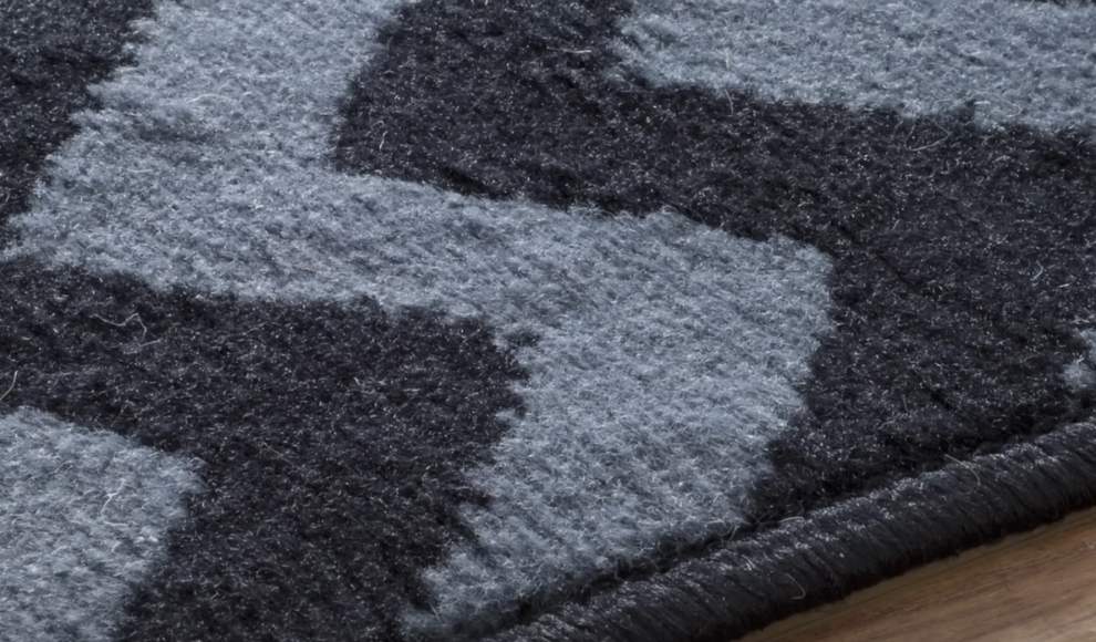 Krupan kadar sivocrnog tepiha sa teksturom i uzorkom na ivici drvenog poda