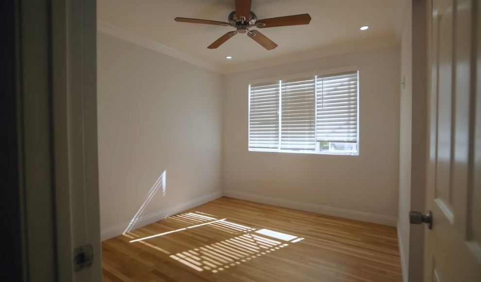 Svetla prazna soba sa drvenim podom i prozorom, spremna za uredjenje radnog kutka