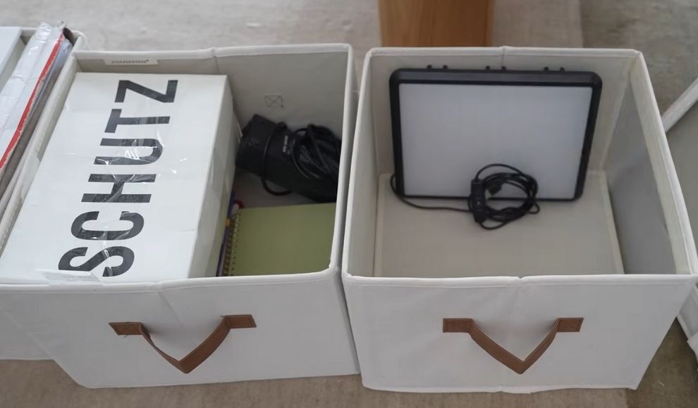Dve bele kutije za odlaganje sa ruckama, u jednoj su knjige i oprema, u drugoj tablet i kablovi