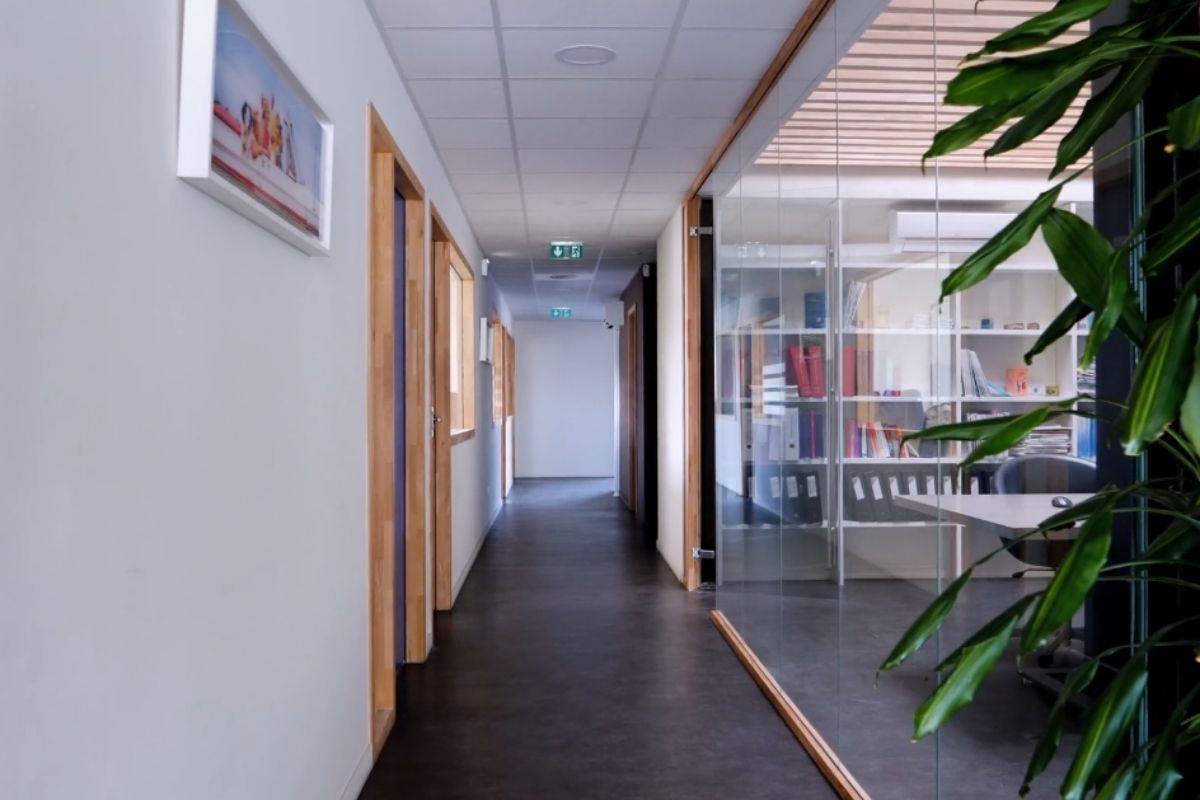 Kancelarijski hodnik sa zidnom slikom i modernim staklenim pregradama, uređen minimalistički